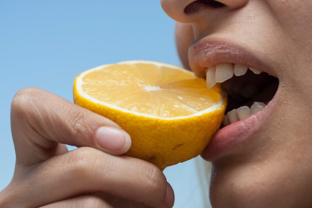 A women eating half cut lemon.
